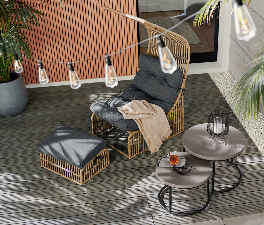 Außenbereich mit Sessel mit Dach, LED-Filament-Lichterkette und 2 Couchtischen mit Beton-Tischplatte.