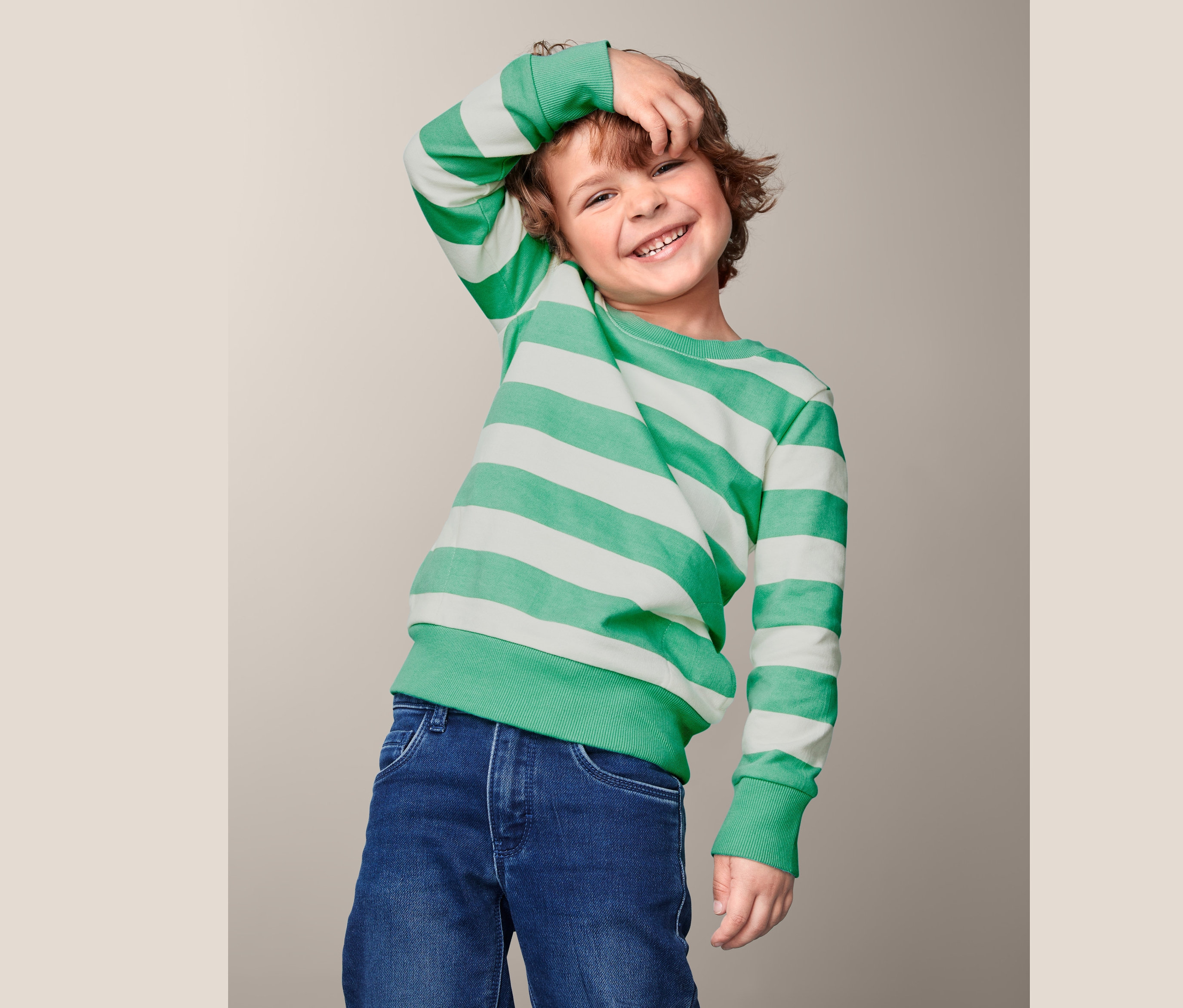 Lächelnder Junge posiert in einem Baumwoll-Sweatshirt mit weißen und grünen Streifen.