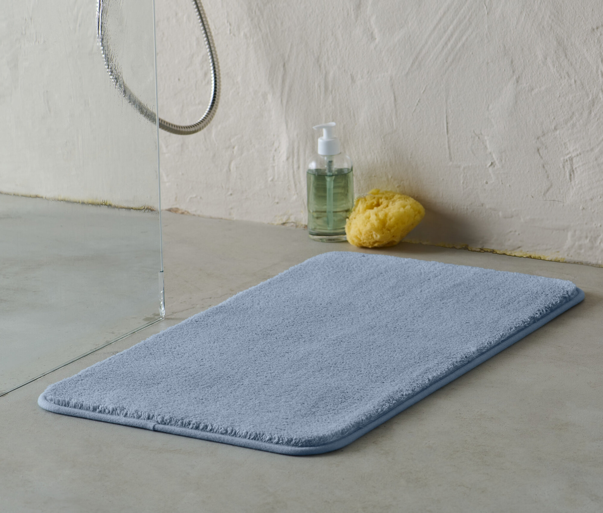 Eine blaue Badematte, ca. 70 x 40 cm, liegt im Badezimmer auf dem Boden.
