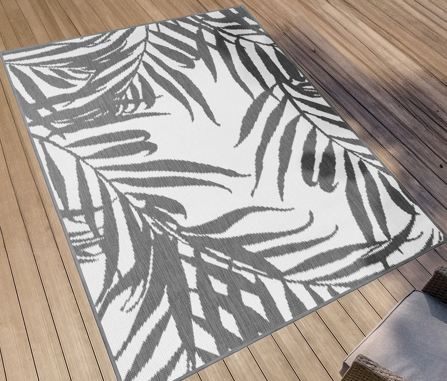 Ein grauer Outdoor-Wende-Teppich »Palm Tree« liegt auf einer Holzterrasse.