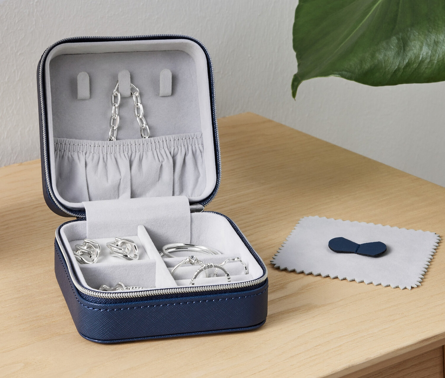 Ein geöffnetes kleines Schmuckkästchen mit Schmuck darin steht auf einem Tisch neben einer Lampe.