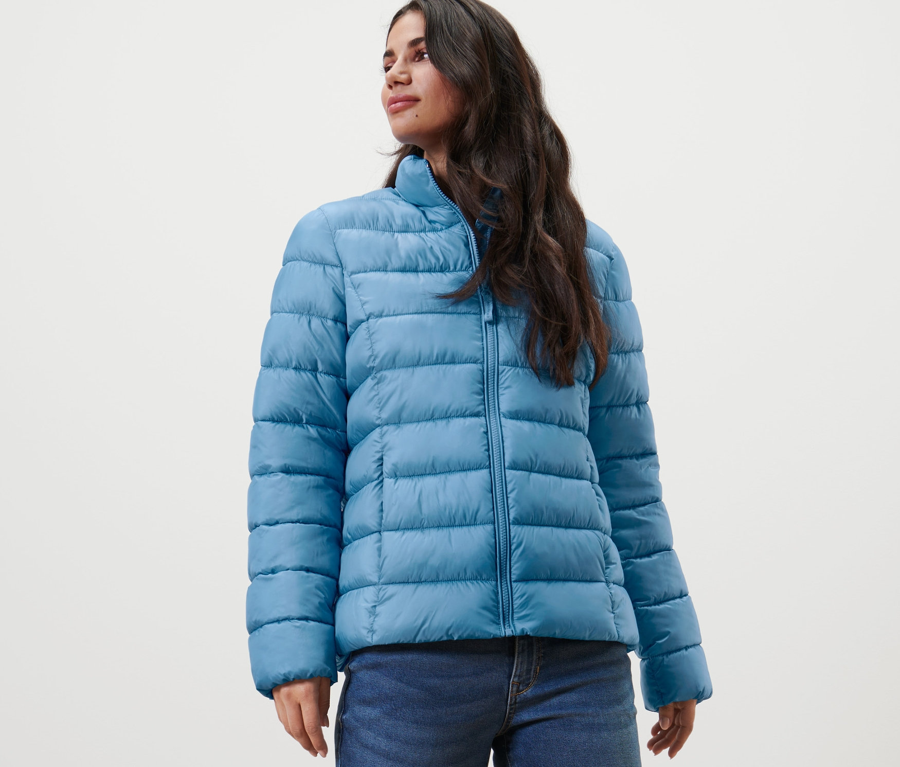 Frau trägt eine Steppjacke und Jeans.