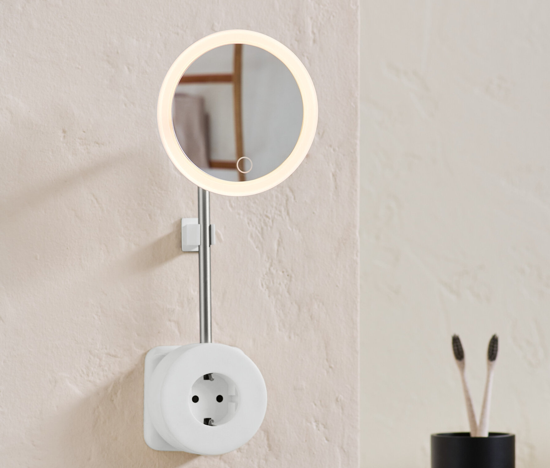 An der Wand ist eine Steckdose mit LED-Kosmetikspiegel.