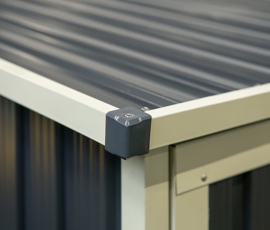 Detail einer Ecke einer grauen Fahrradgarage mit grauem Dach.