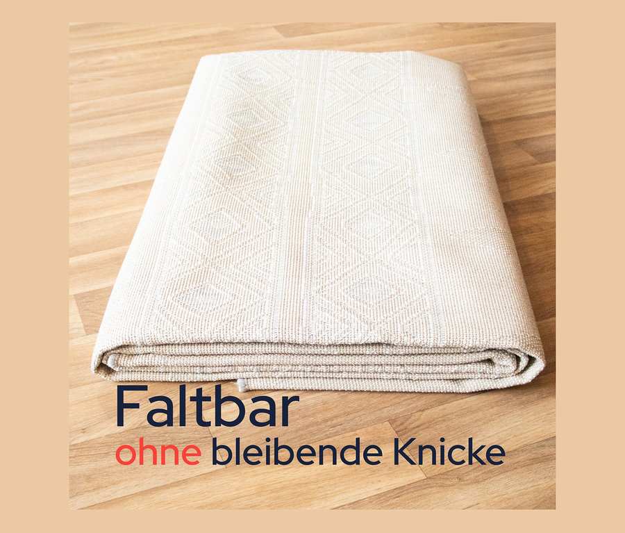 Ein gefalteter, brauner Outdoor-Teppich "Diamond Rhythm" (240 x 340 cm) liegt auf einem Holzboden.