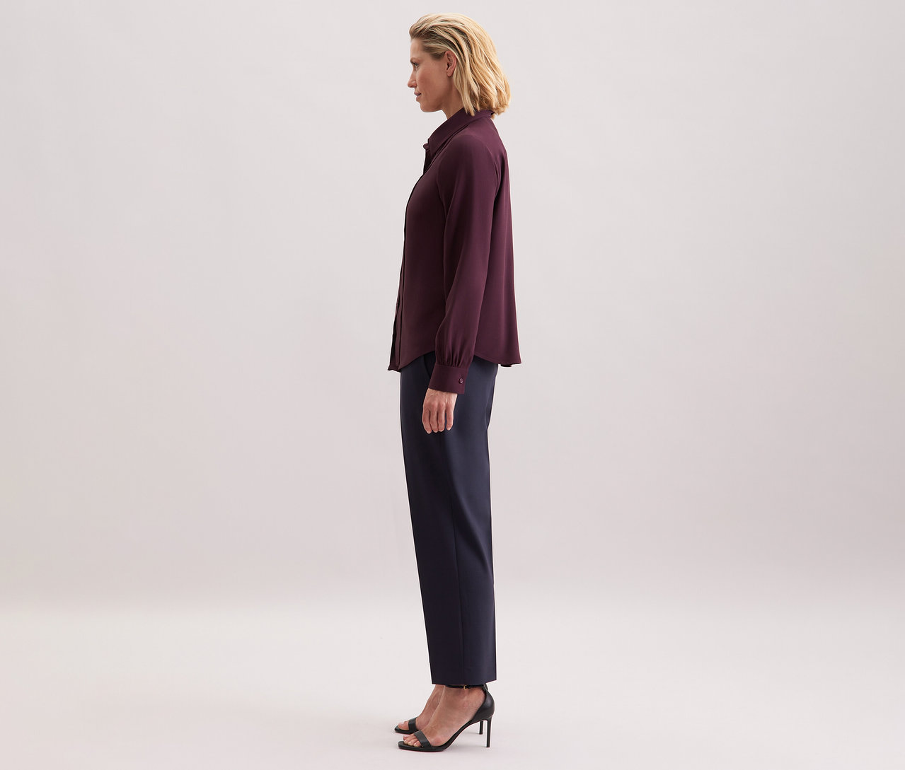 Frau trägt eine Seidensticker Schluppenbluse aus Viskose, eine dunkle Hose und schwarze Sandaletten.