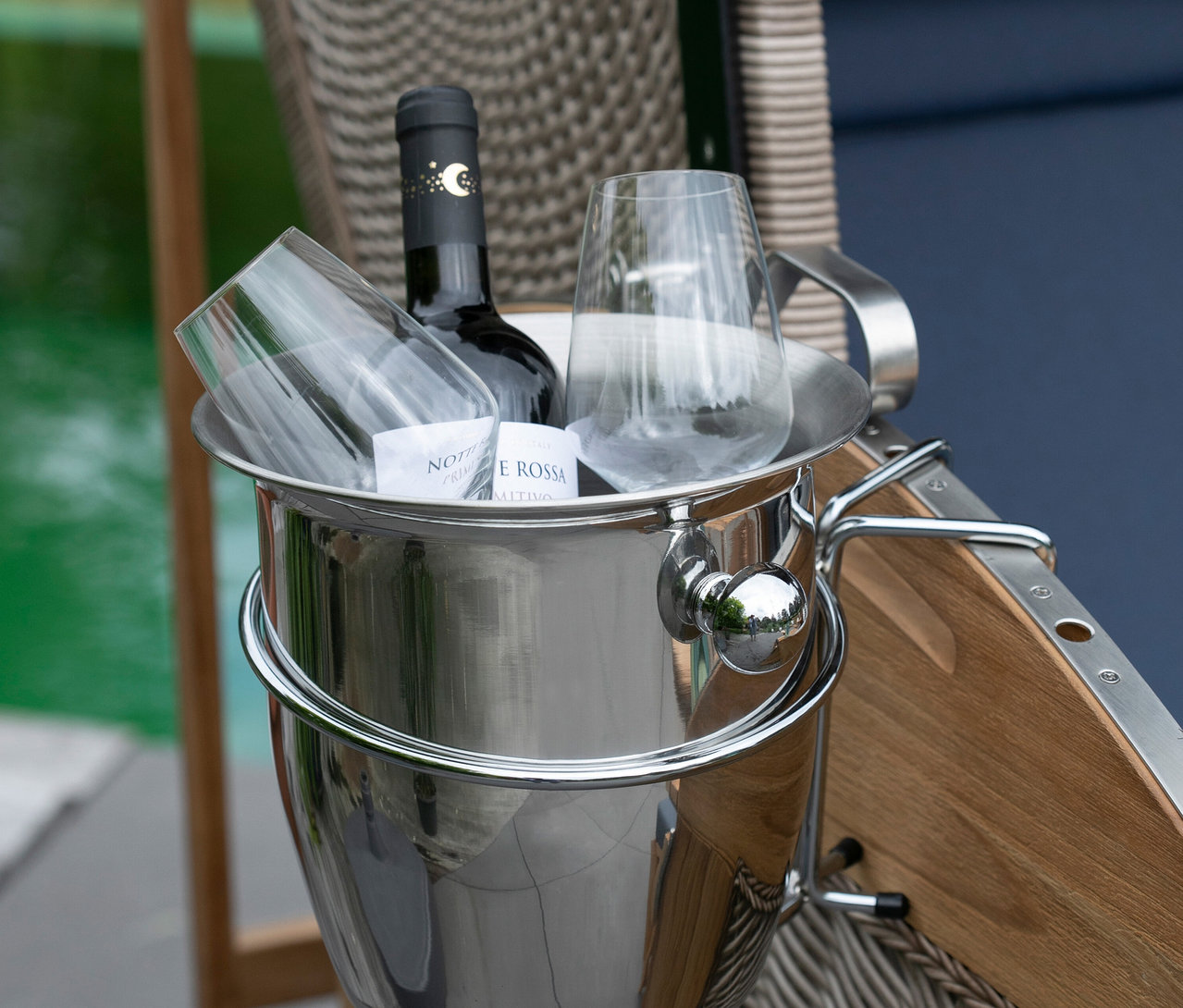 Eine Flasche Wein und zwei Gläser in einem silbernen Eiskübel auf einem Stuhl.