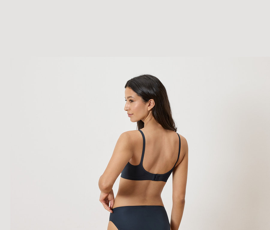 Frau trägt einen marineblauen BH und Slip, von hinten gesehen.