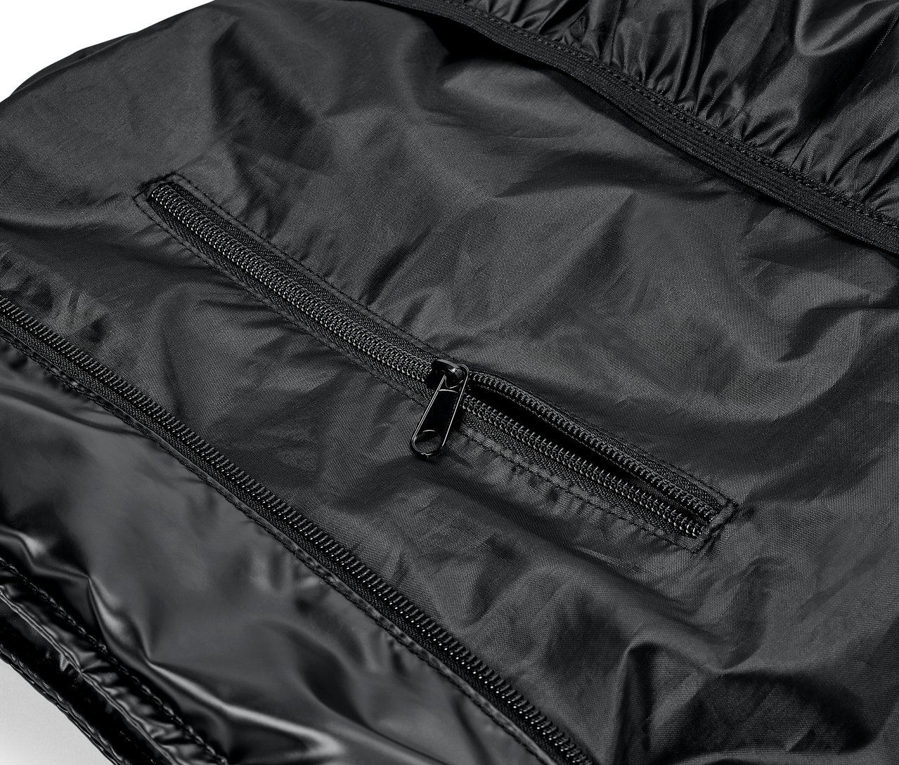 Detailaufnahme eines glänzenden schwarzen Kleidungsstücks mit Reißverschlüssen.