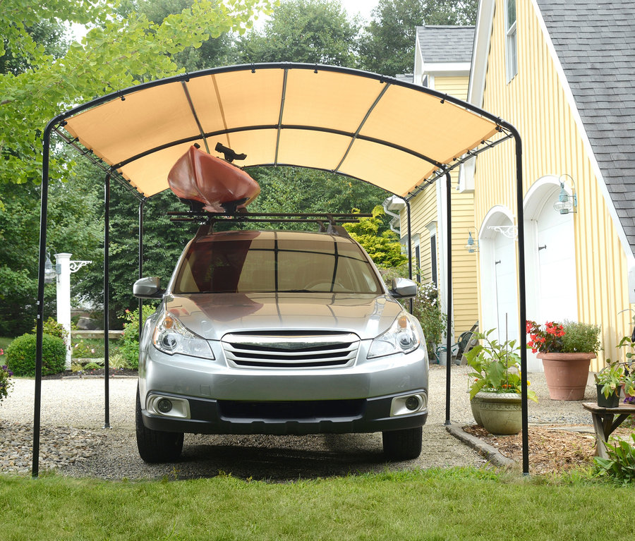 Graues Auto parkt unter einem Runddach-Carport mit einem braunen Kanu auf dem Dach.