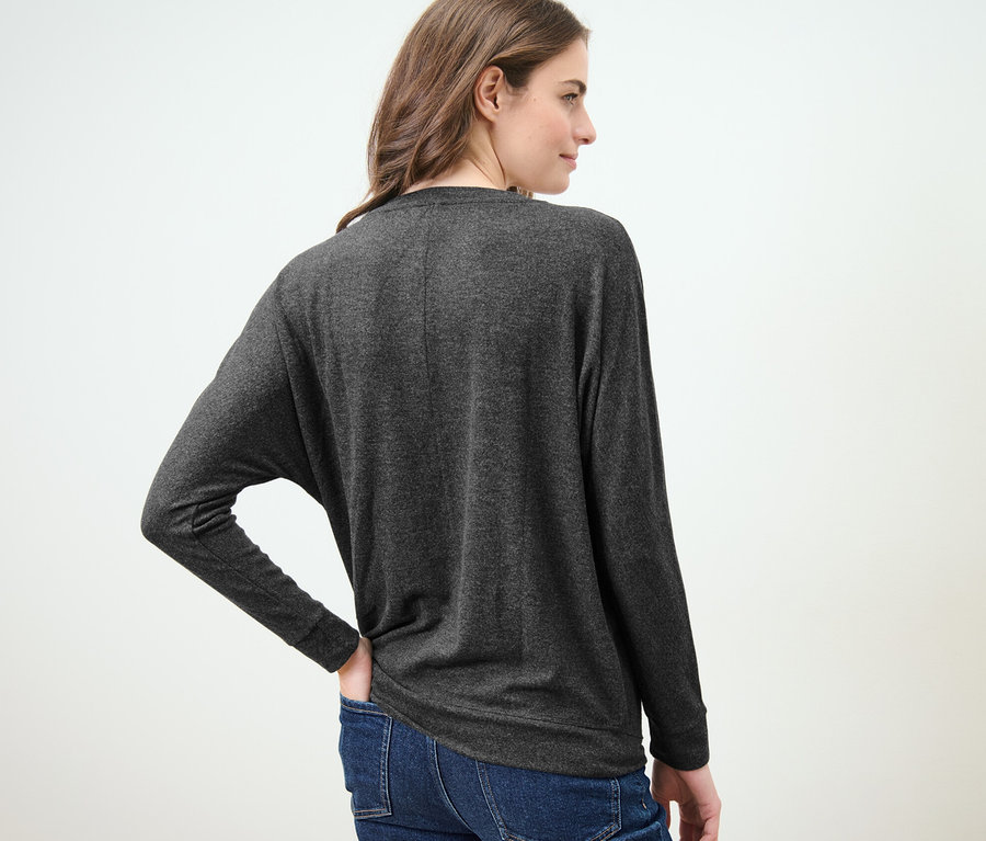 Frau trägt ein Fledermausshirt und Jeans.