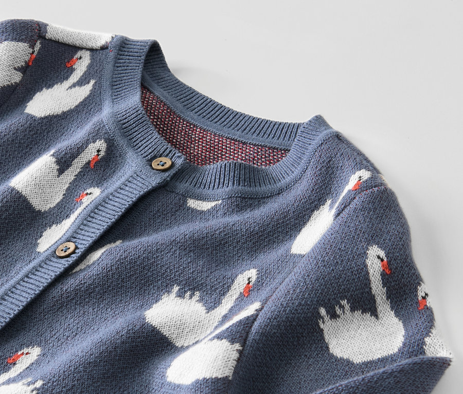 Detailansicht einer blauen Kinder-Strickjacke mit Schwanenmuster.