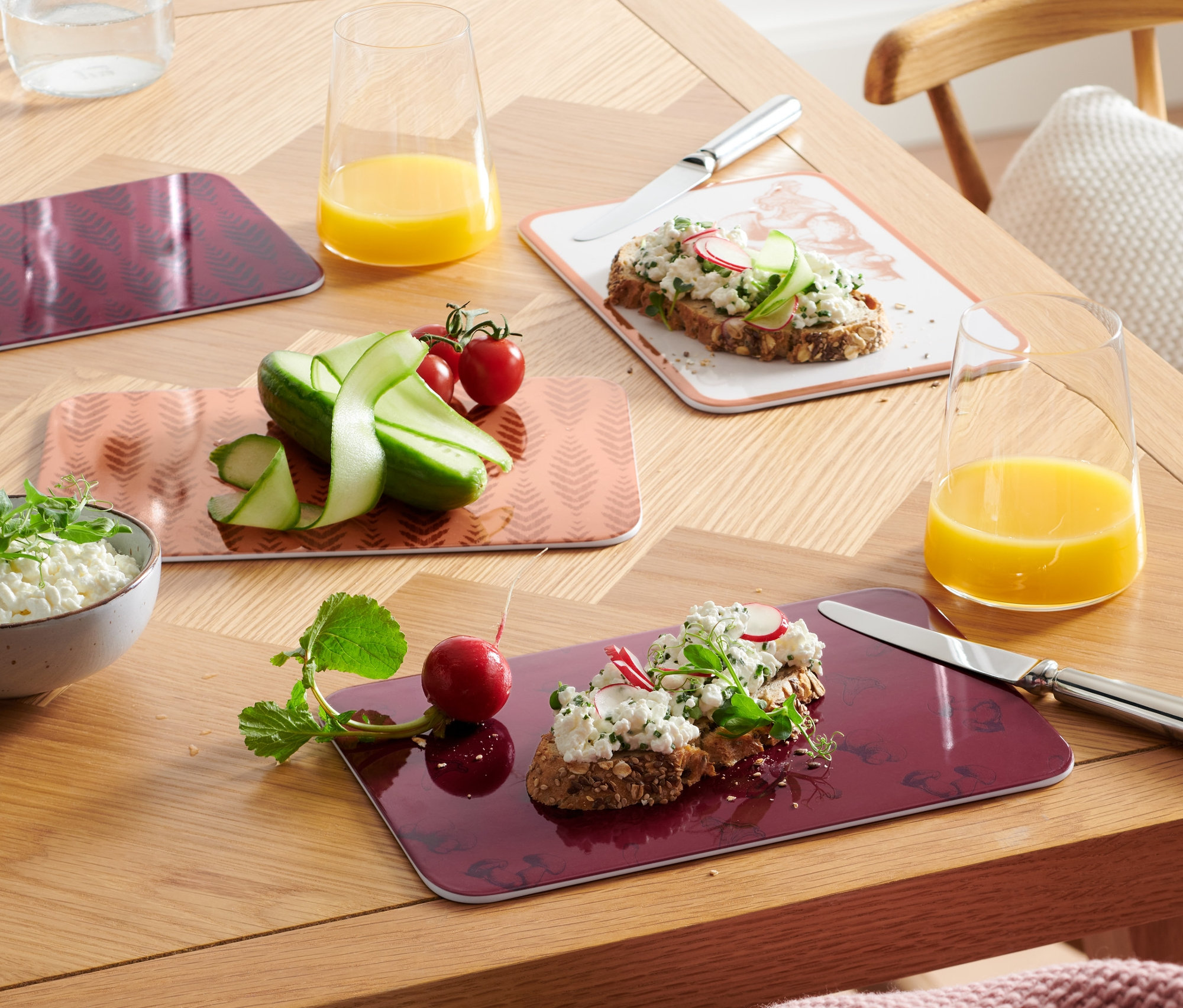 Vier Schneidebretter mit Speisen auf einem Holztisch.