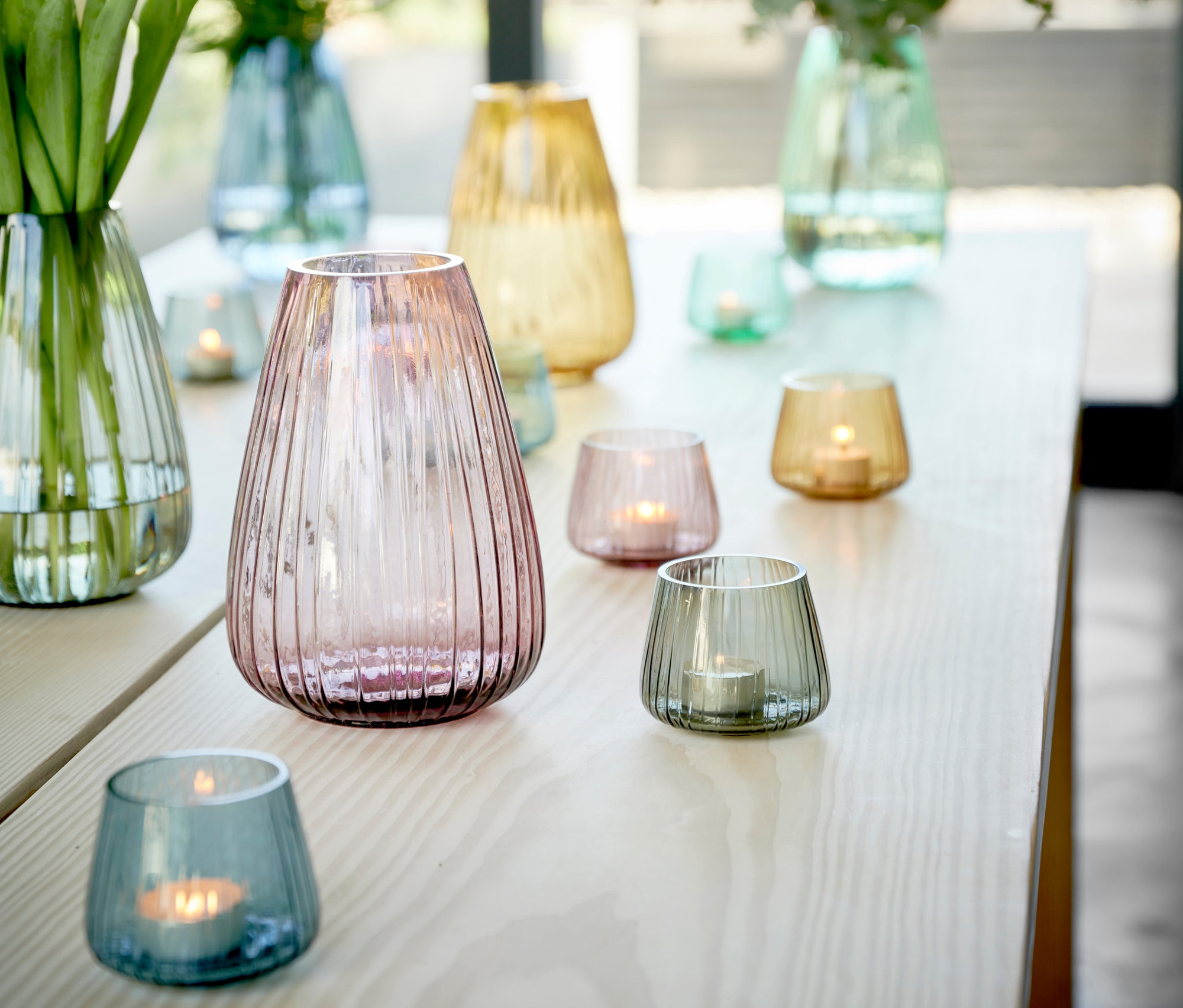 Dekorative Glasvasen und Kusintha Teelichthalter in Grün, Blau und Rosa auf einem Tisch.