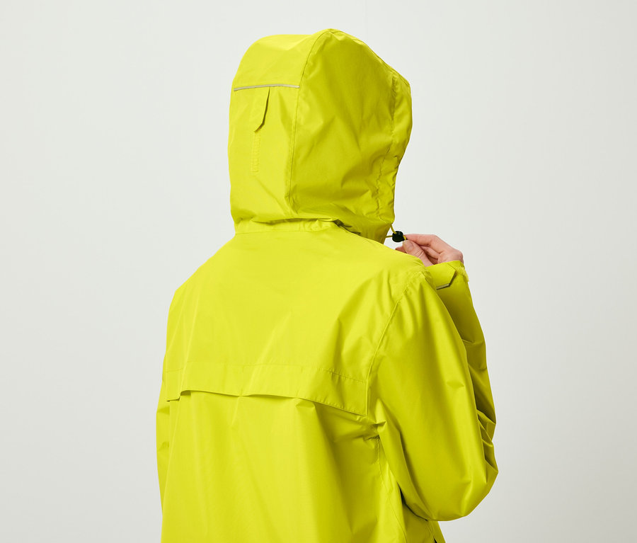 Person von hinten in zitronengelber Kapuzenjacke, die den Kordelzug anpasst.