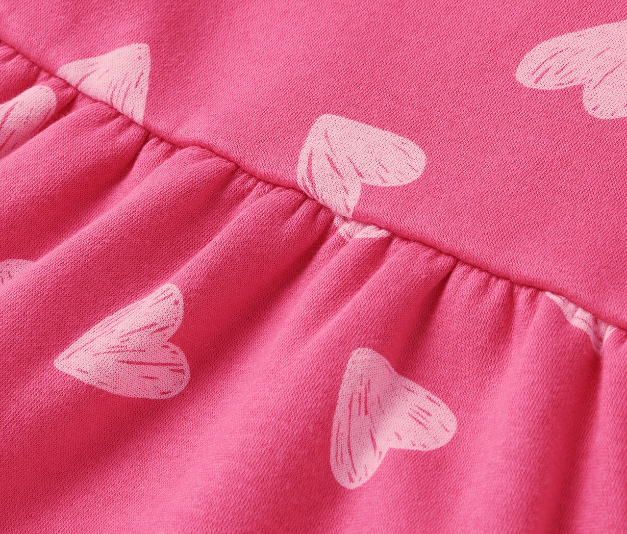 Detailaufnahme eines rosa Stoffes mit weißen Herzen und Raffung.