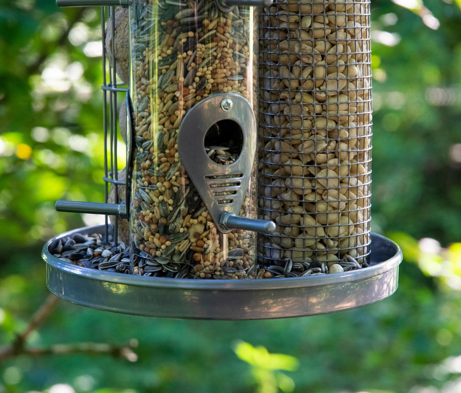 Nahaufnahme eines hängenden Dobar-3-Kammer-Futterspenders, gefüllt mit verschiedenen Samen und Nüssen.