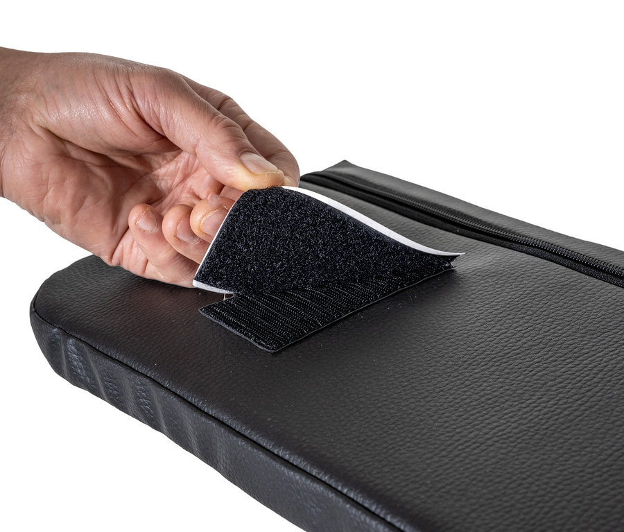 Eine Hand löst den Klettverschluss an einem schwarzen HAWK Sitzkissen.