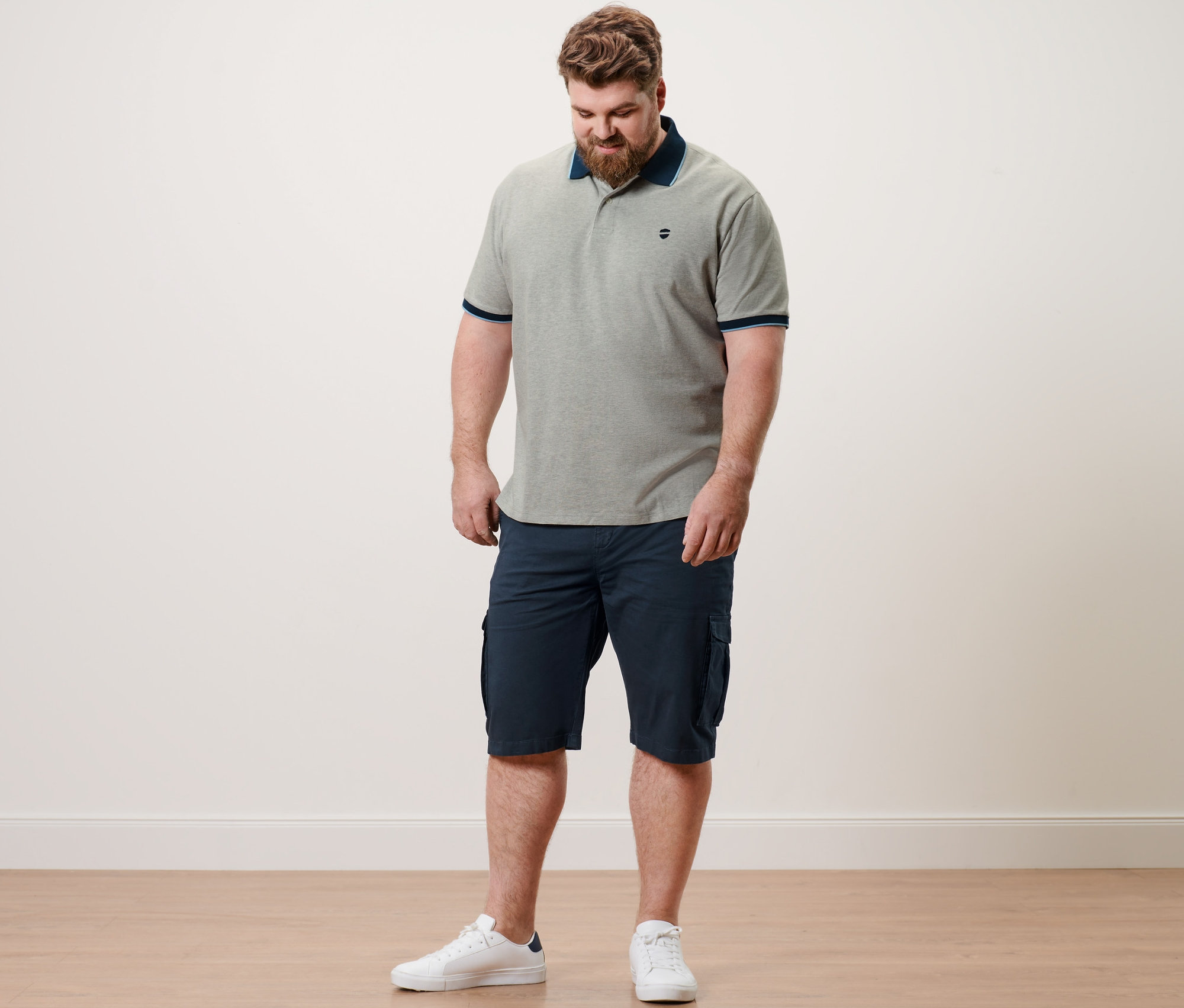 Mann trägt ein grau meliertes Piqué-Poloshirt und navy Cargo-Shorts.