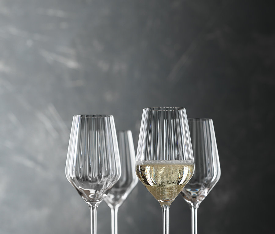 Vier Spiegelau Champagnergläser »Lifestyle«, 8er-Set stehen auf einem Holztisch, eines davon ist mit Champagner gefüllt.