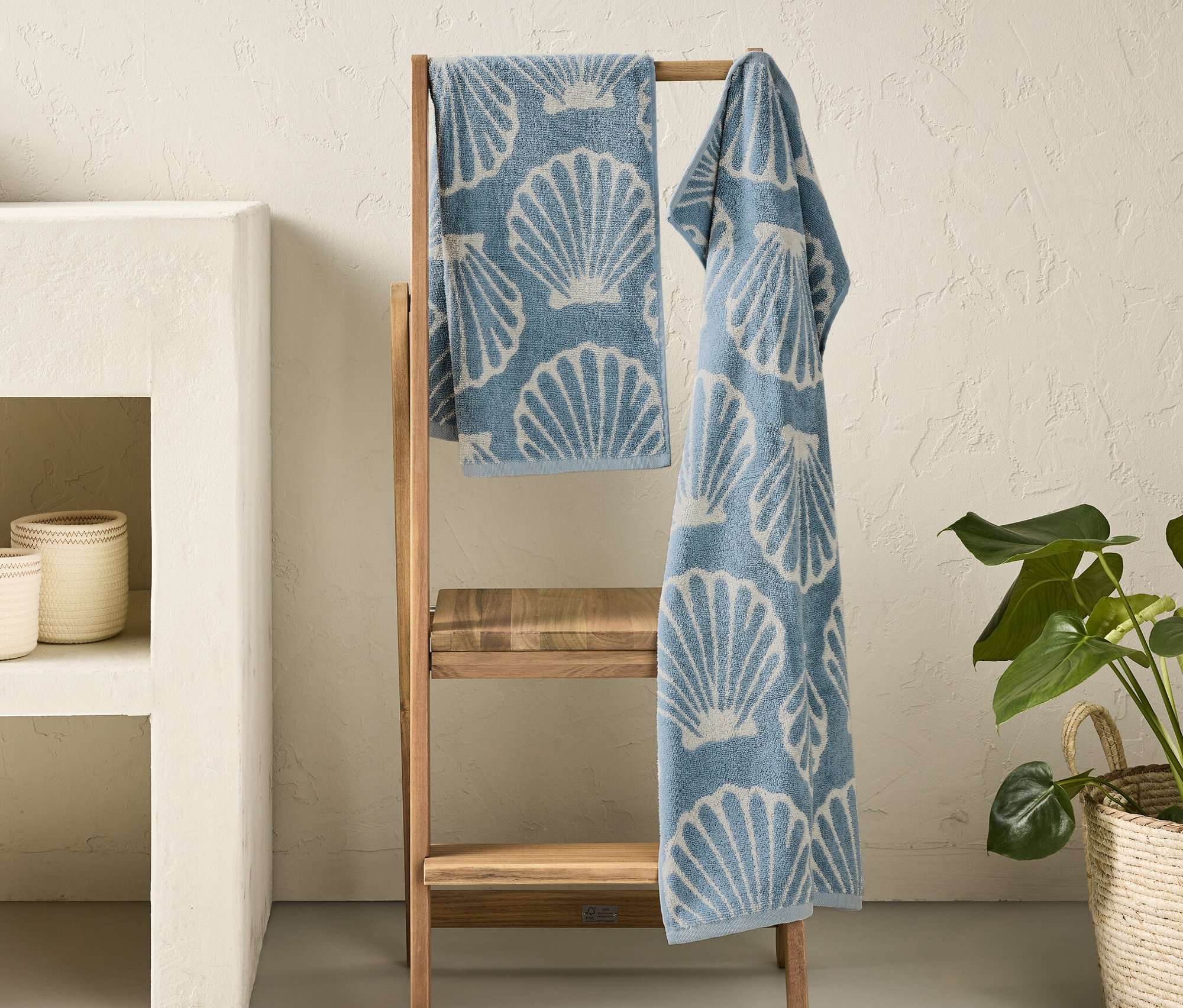 Zwei blaue Handtücher »Muschel« mit Muscheldruck hängen auf einer Holzleiter im Badezimmer.