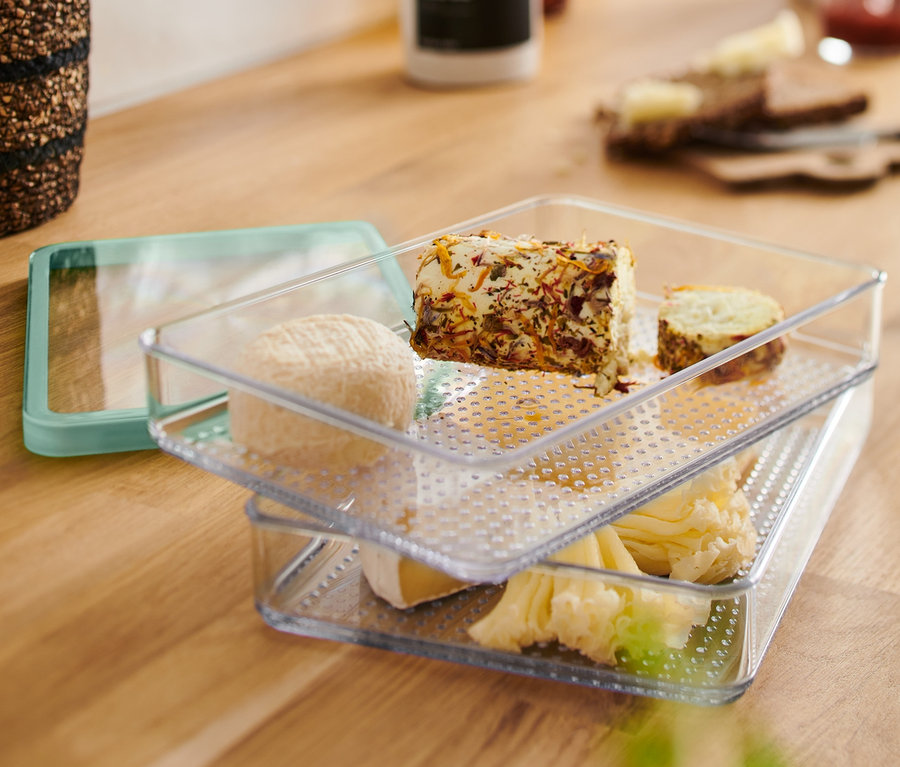 Zwei durchsichtige Aufschnittbehälter sind übereinander gestapelt und mit verschiedenen Käsesorten gefüllt.