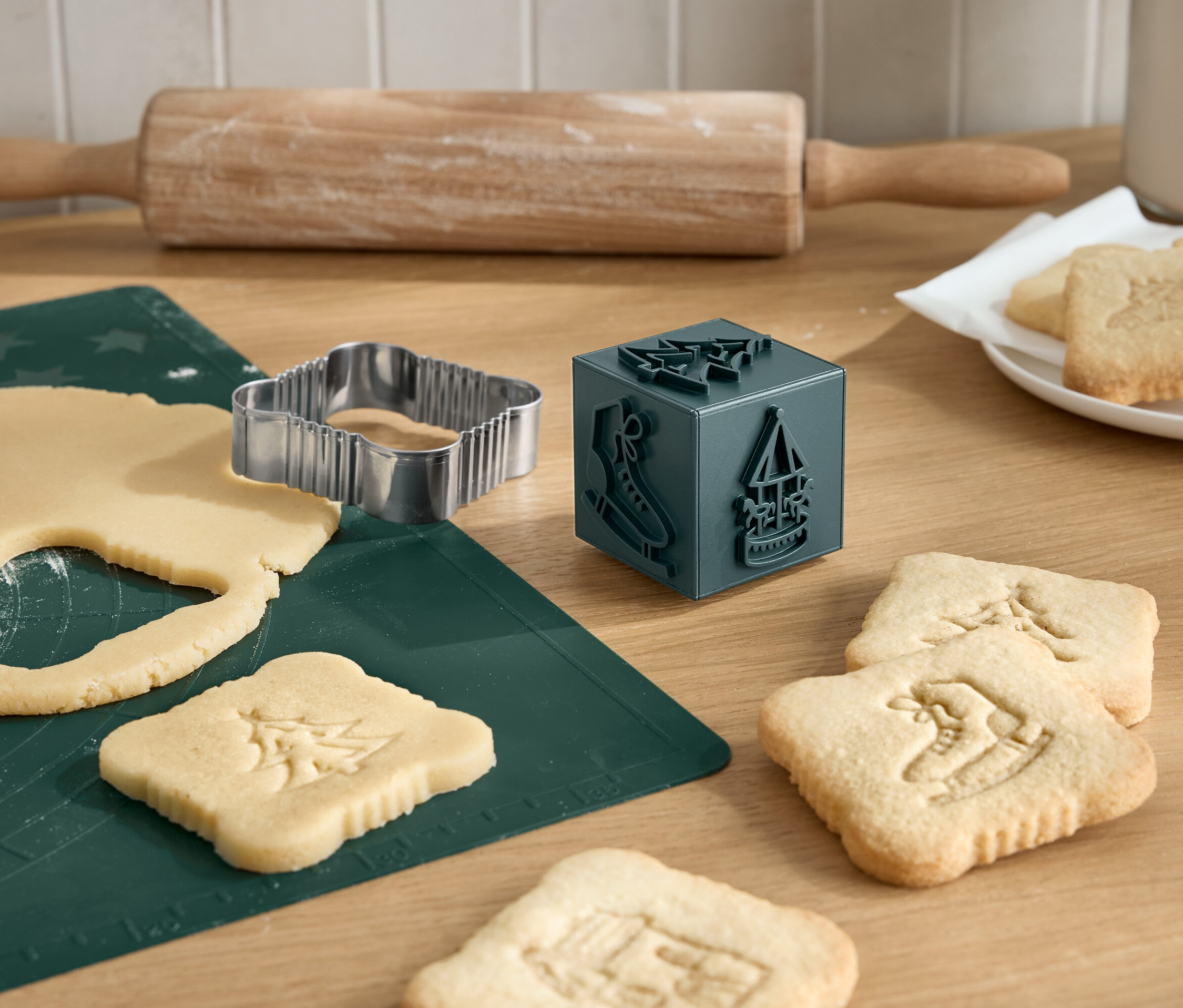 Weihnachtsplätzchen werden mit einem Ausstecher, einem Nudelholz und einem Plätzchenstempel ausgestochen.