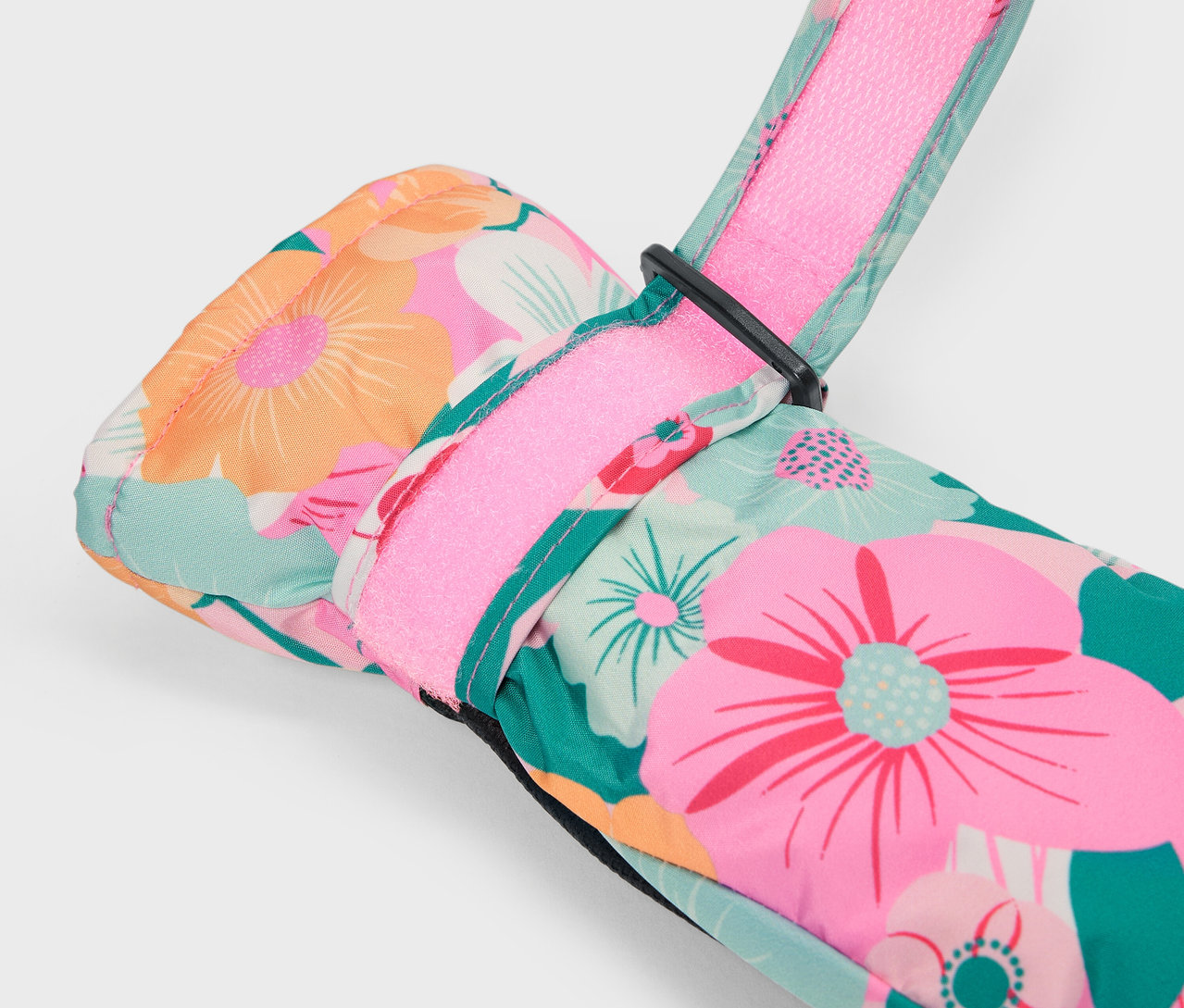 Detail eines bunten Blumen-Skihandschuhs mit rosa Riemen.