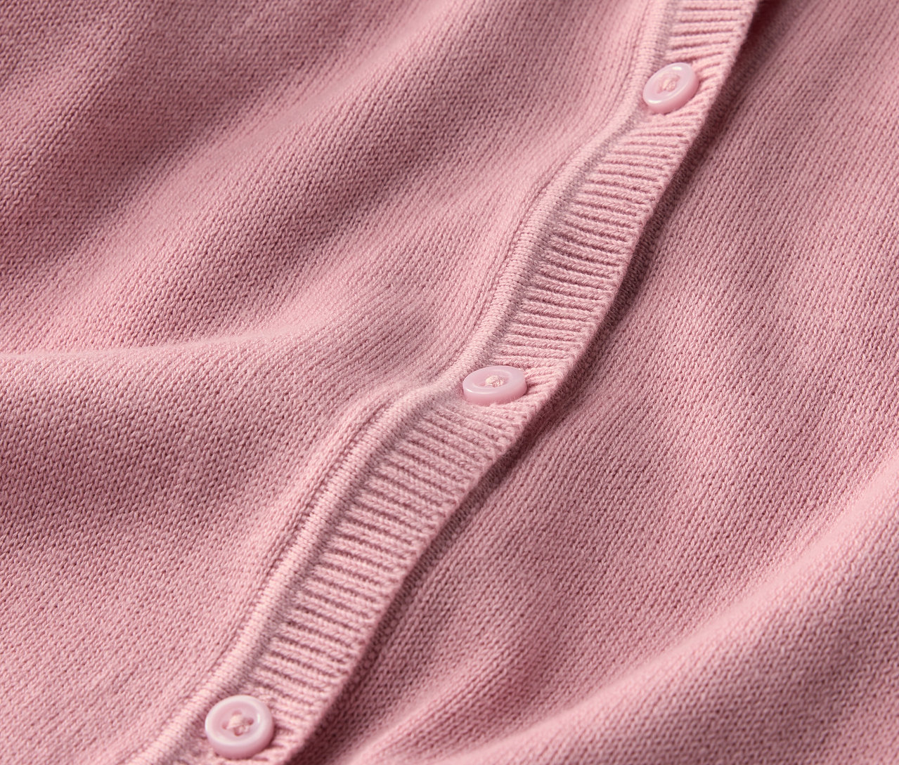 Detailansicht einer Kinder-Strickjacke mit Knöpfen.