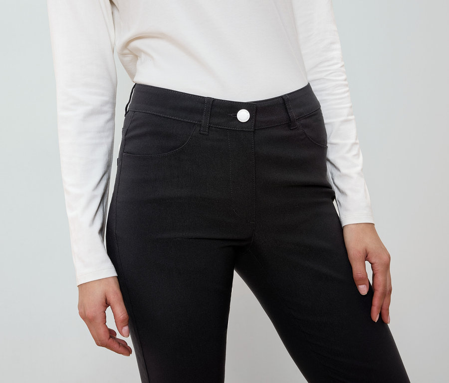 Eine Frau trägt eine schwarze Hose und ein weißes Hemd.