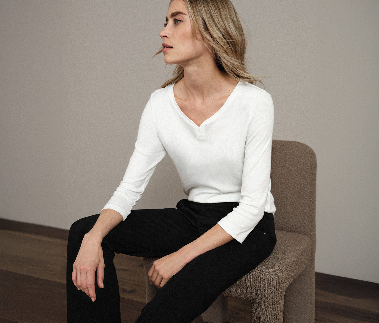 Frau sitzt auf einem Stuhl und trägt ein weißes Street One 3/4-Shirt mit Knopfdetail.