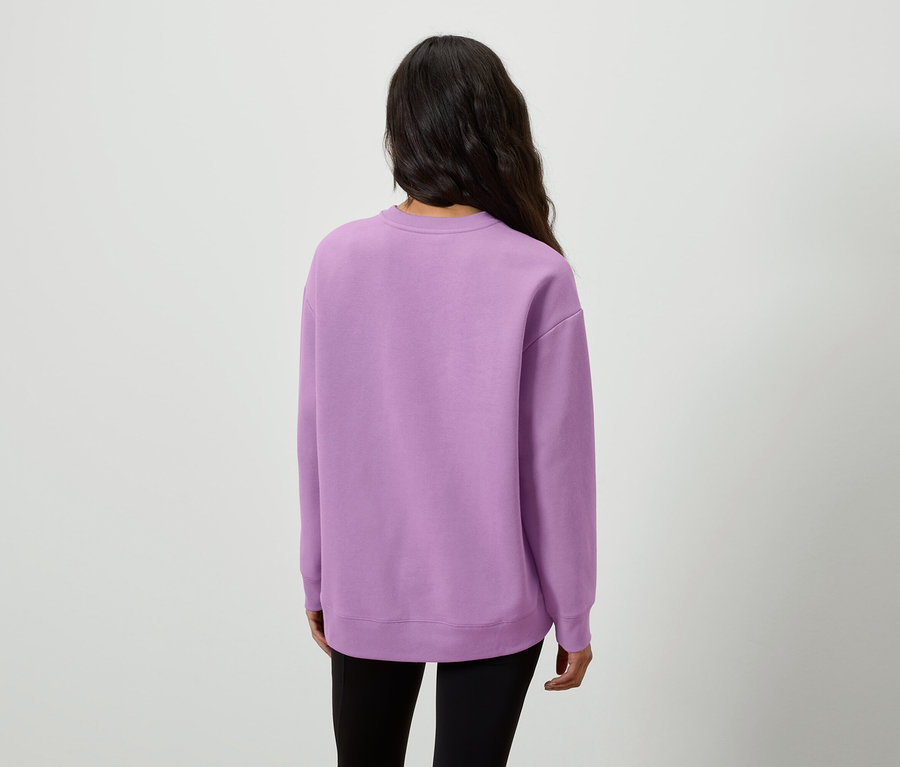 Rückansicht einer Frau mit langen, dunklen Haaren, die einen lila Pullover und schwarze Leggings trägt.