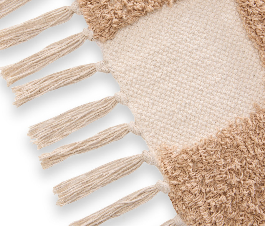 Detailaufnahme eines Teppichs mit beigen und cremefarbenen geometrischen Mustern und Fransen.