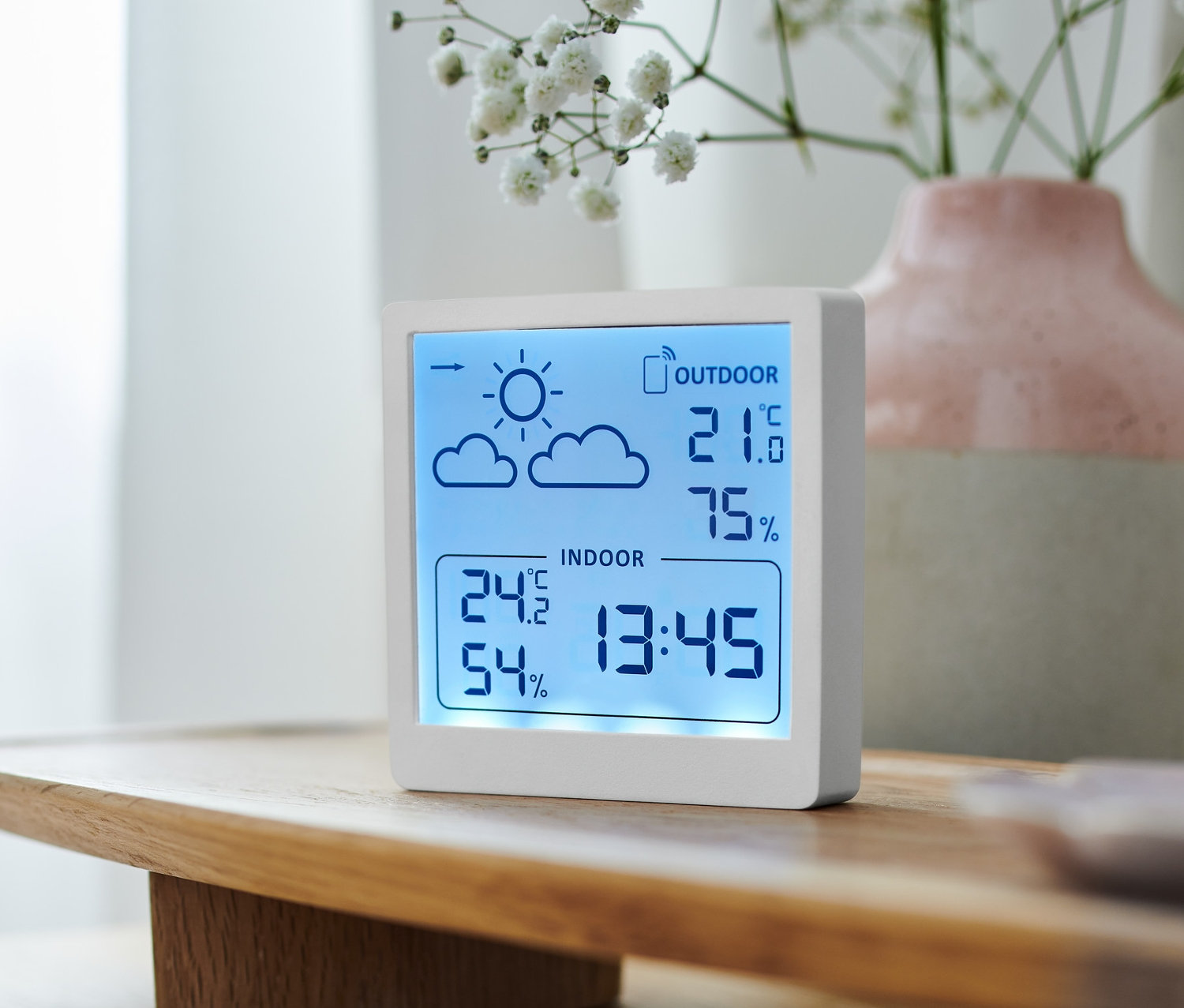 Eine weiße Wetterstation zeigt die Innen- und Außentemperatur und Luftfeuchtigkeit an.
