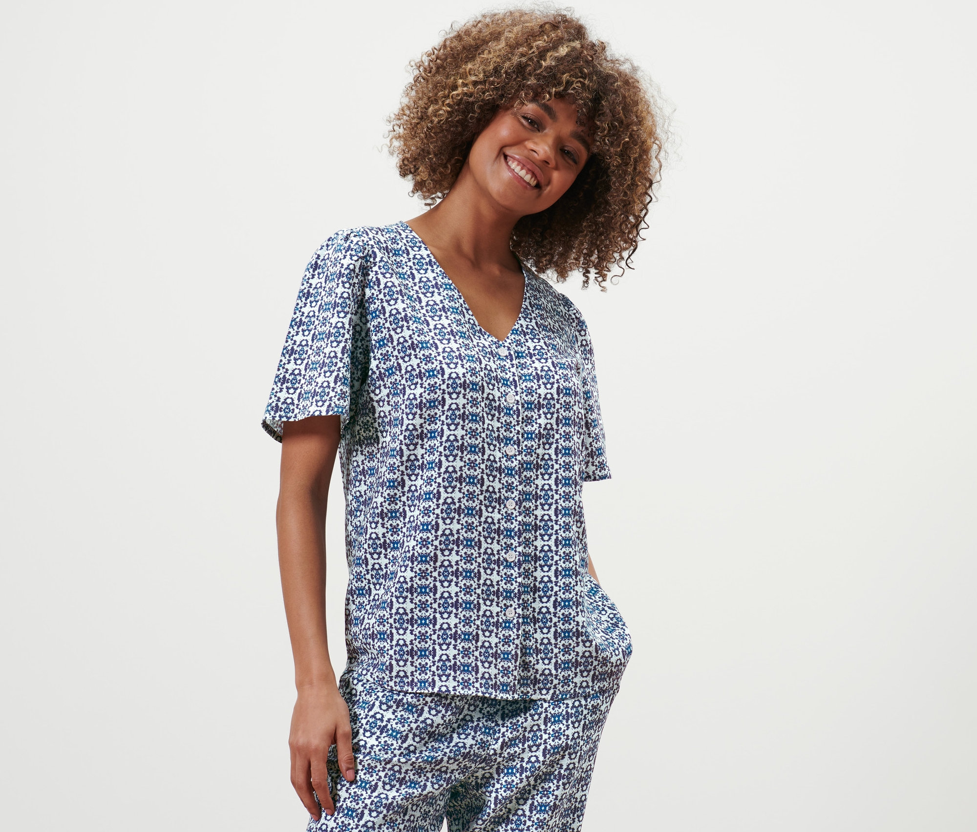 Frau posiert in Bluse mit Alloverprint.