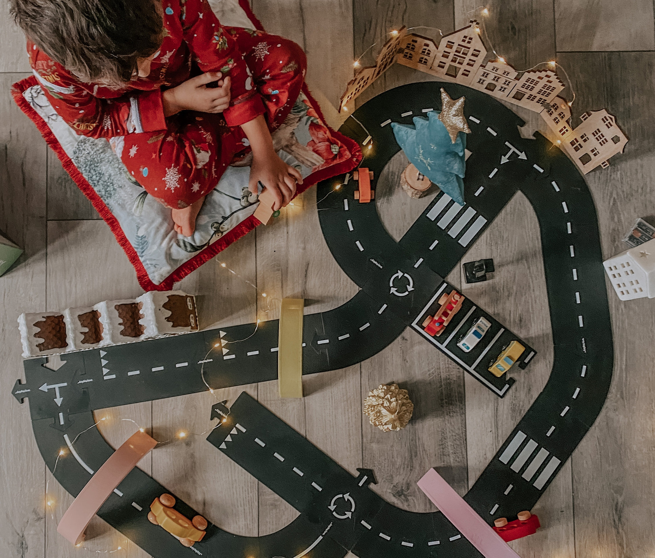 Junge im Schlafanzug spielt mit Waytoplay-Spielstraße »Highway« auf dem Boden.