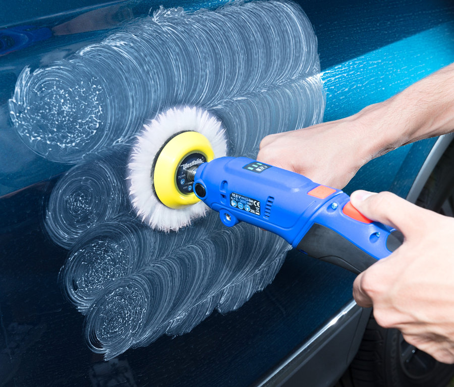 Mann poliert ein blaues Auto mit einer Westfalia Akku-Poliermaschine.