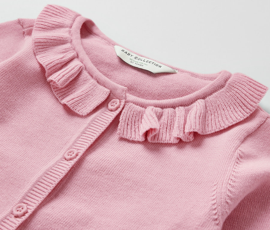 Nahaufnahme einer rosa Baby-Strickjacke mit Rüschenkragen und Knopfverschluss.