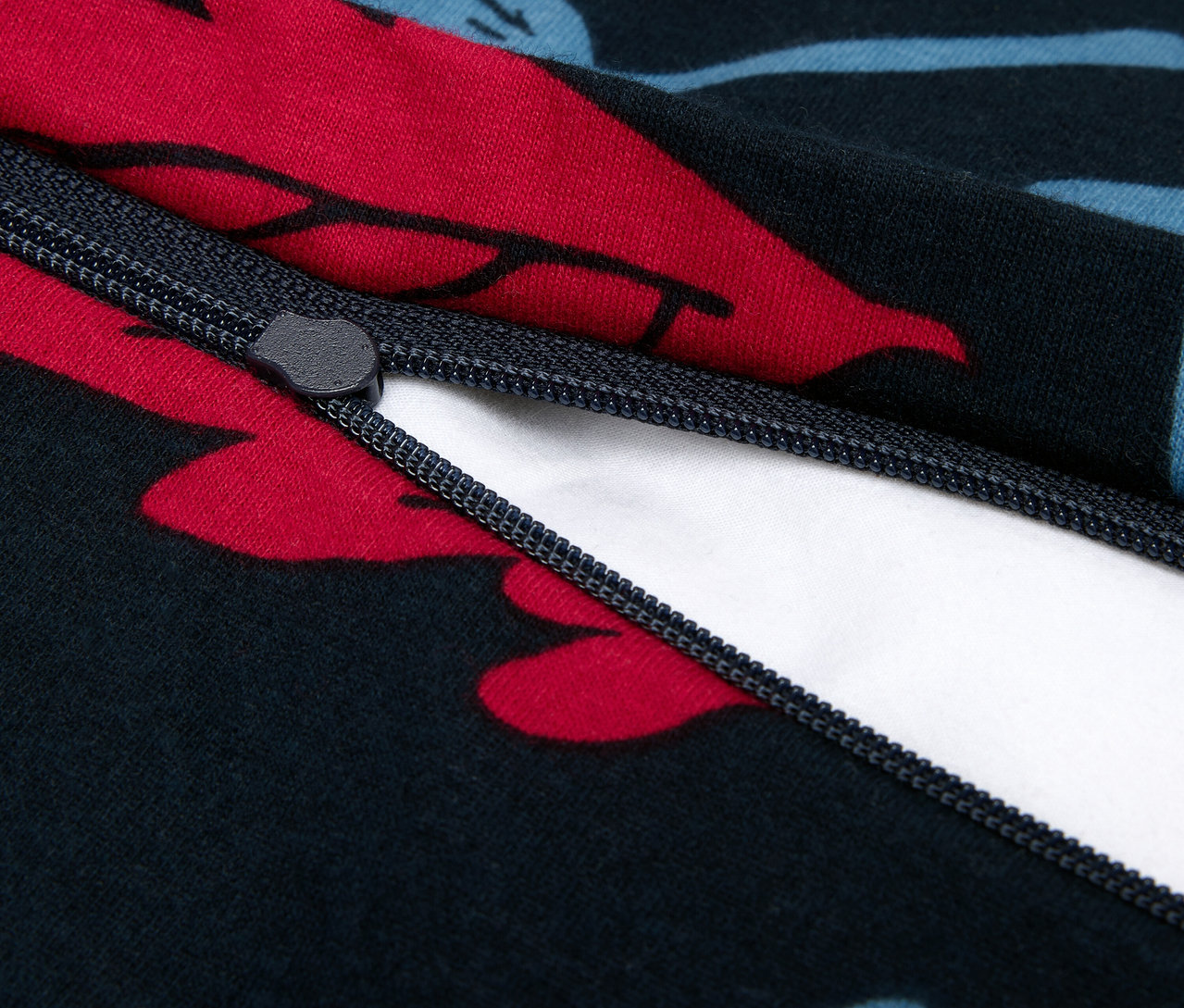 Nahaufnahme eines Reißverschlusses auf einem dunkelblauen Bettbezug mit roten und blauen Blumen.