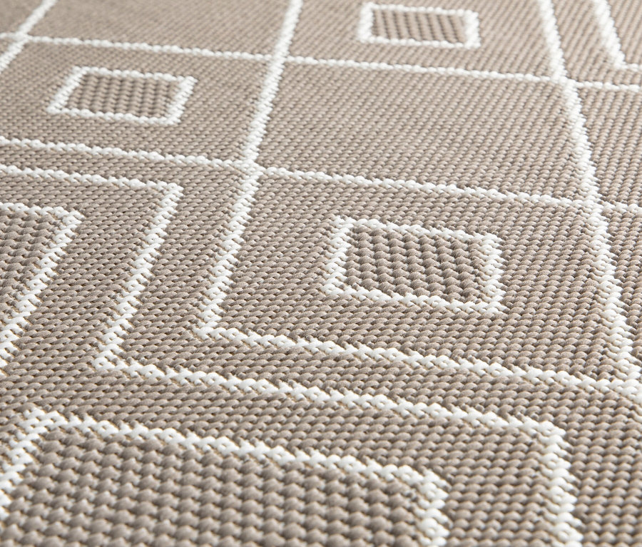 Nahaufnahme eines braunen, faltbaren Outdoor-Teppichs »Diamond Rhythm« mit einem Muster aus weißen geometrischen Formen.