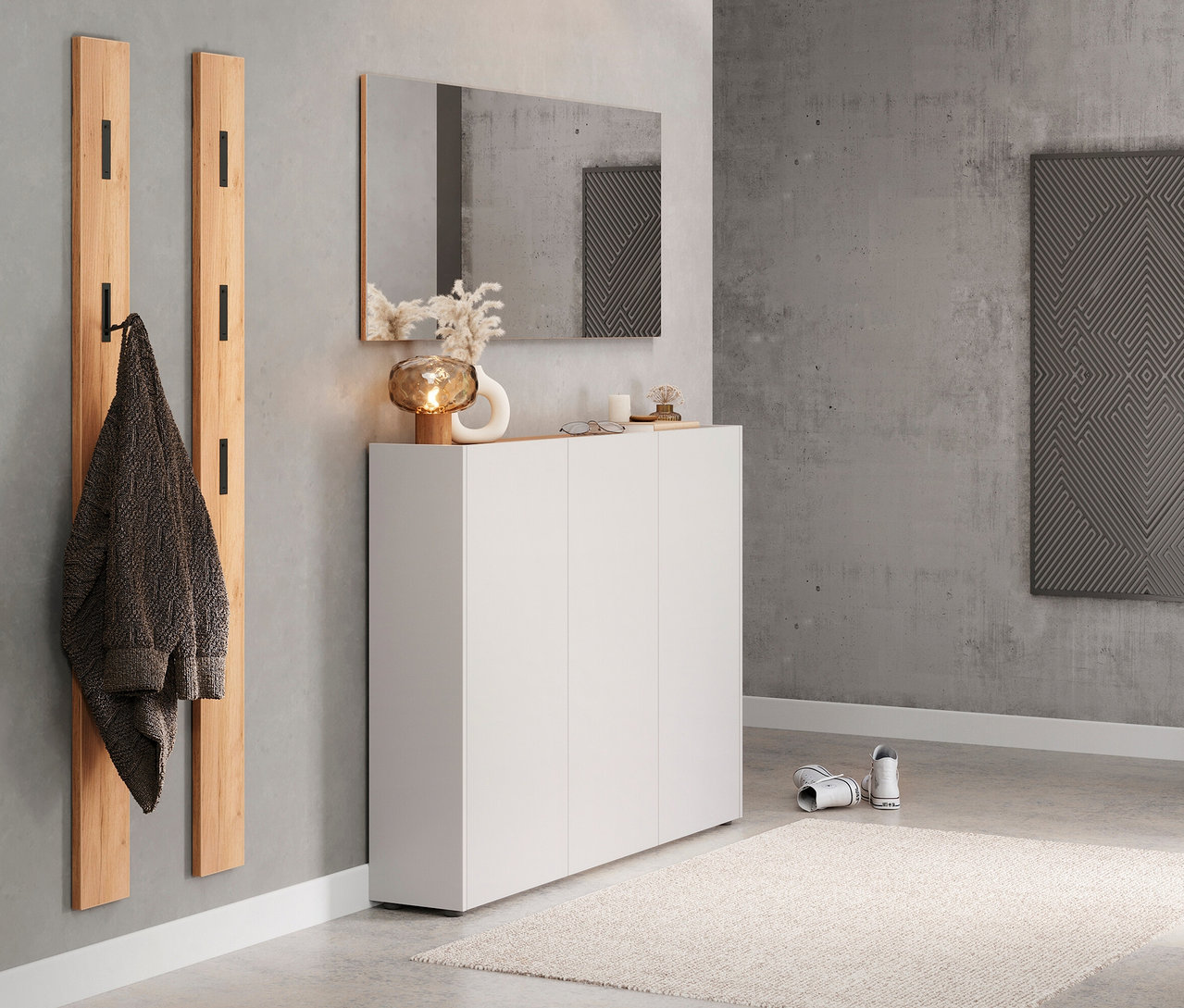 Flur mit Holzgarderobe, Spiegel und weißem Schuhschrank mit Dekoration.