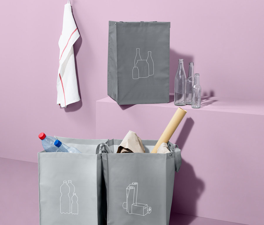 Drei graue Recycling-Abfall-Sortiertaschen mit weißen Symbolen, gefüllt mit Wertstoffen.