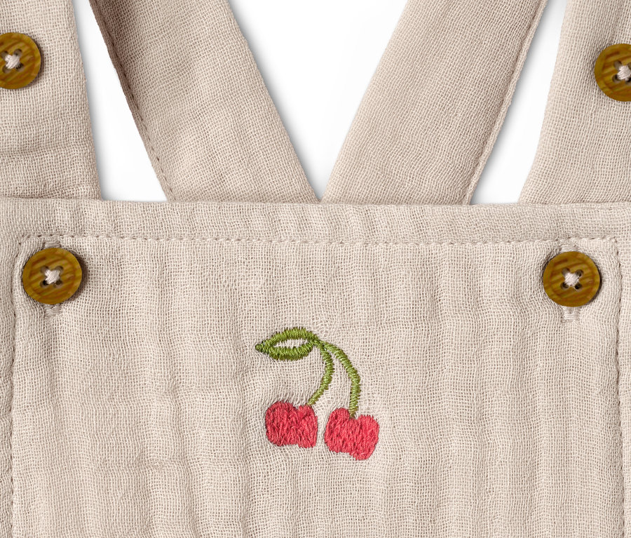 Detailansicht eines Baby-Stramplers mit Kirschstickerei und Knöpfen.