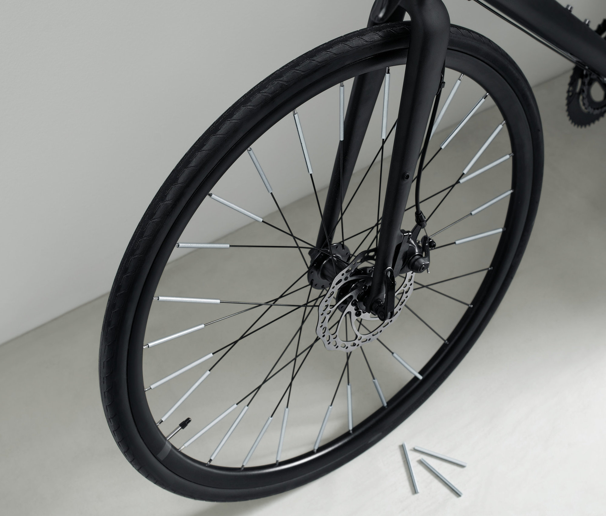 Nahaufnahme eines schwarzen Fahrrads mit 36 Speichen-Reflektoren an den Speichen.