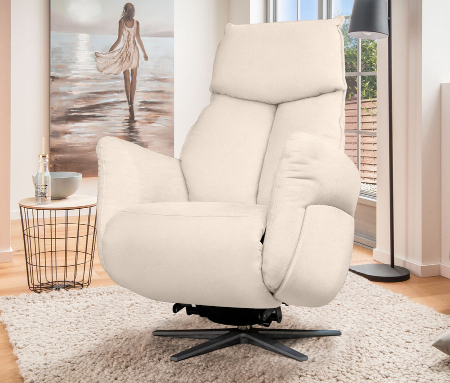 Ein cremefarbener Liegesessel "Theo" XBO-1 steht auf einem zotteligen Teppich in einem Wohnzimmer.