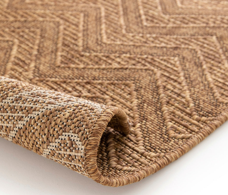 Detailansicht eines braunen Teppichs »Roy« mit Linienmuster, ein Teil des Teppichs ist aufgerollt.