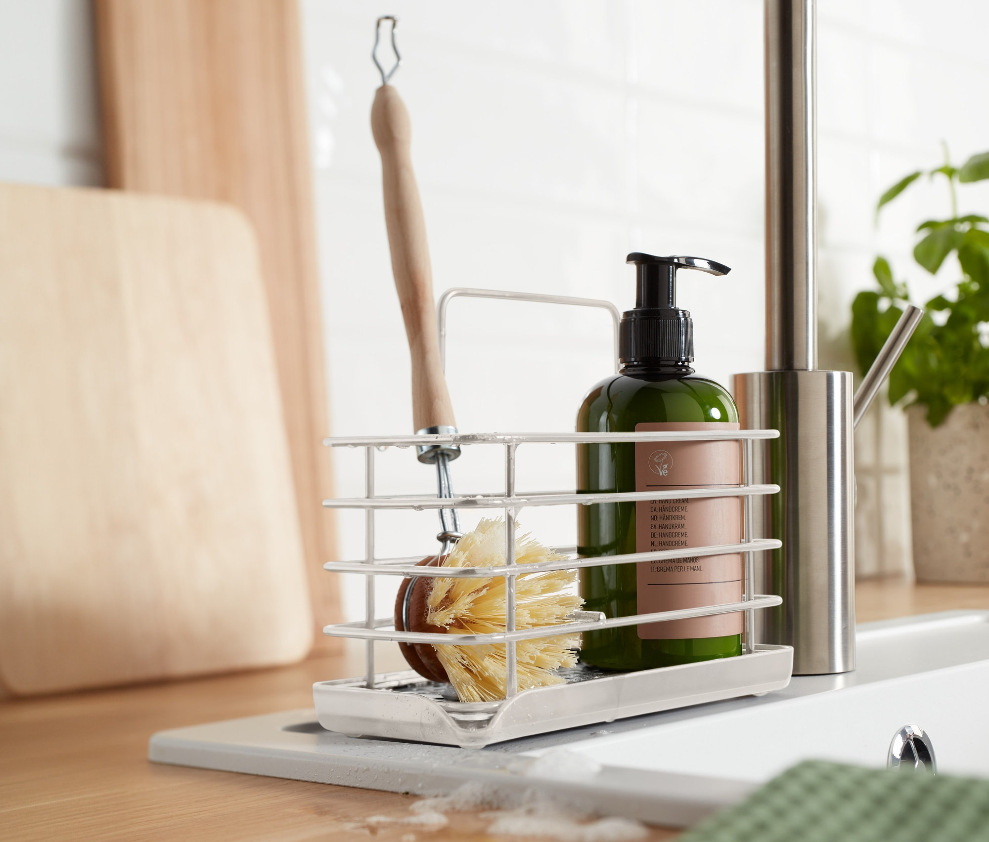 In der Küche steht ein Spülutensilien-Ständer aus Metall mit einer Bürste und einer Seifenflasche.