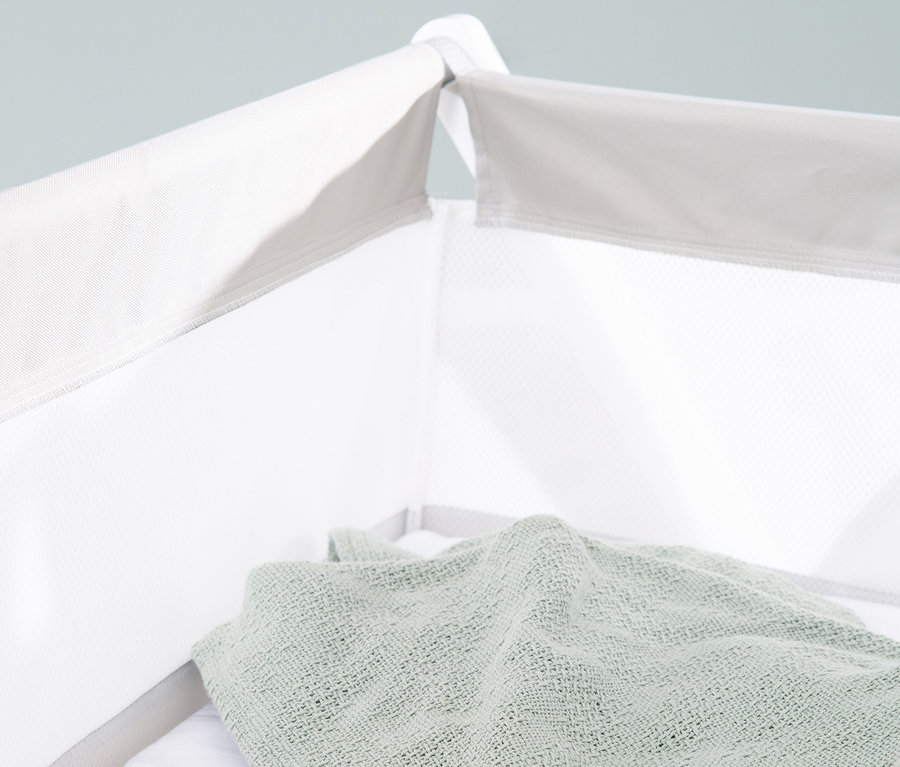 Draufsicht auf eine gefaltete grüne Decke in einem weißen, klappbaren roba Stubenbett.