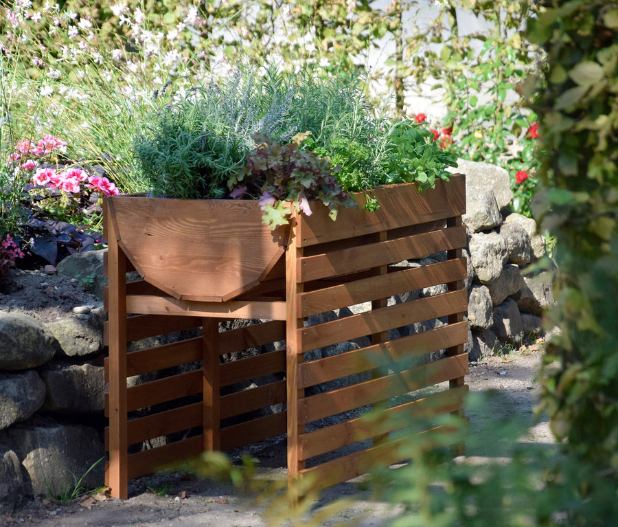 Ein braunes, doppeltes XL-Hochbeet mit Pflanzen in einem Garten.