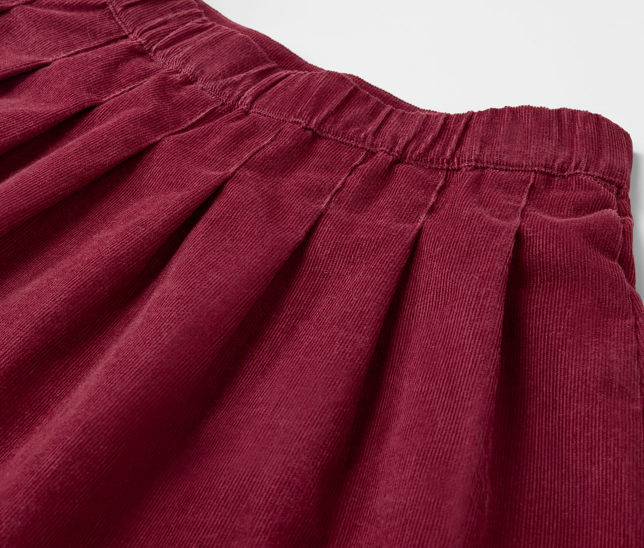 Detailaufnahme eines bordeauxroten Kinder-Faltenrocks.